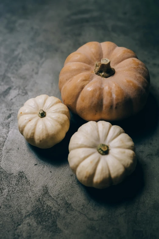 a group of three pumpkins are on the ground