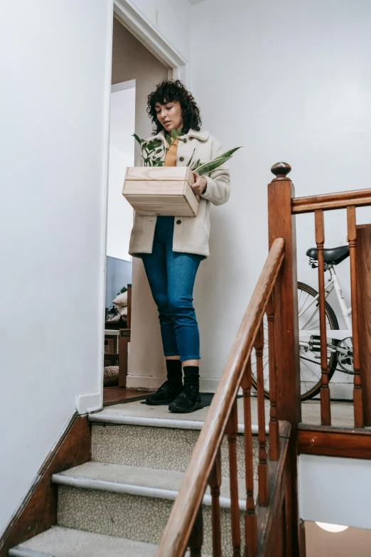 a woman holding a box of flowers while on the stair