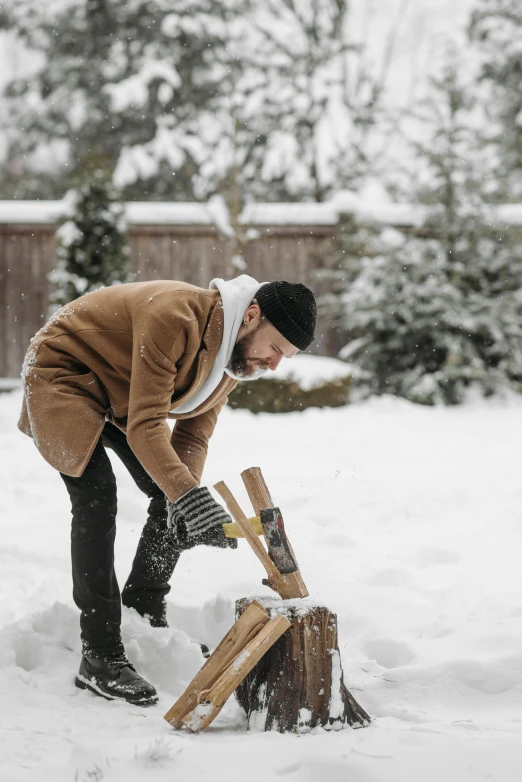 a man standing in the snow with his hands around a tree