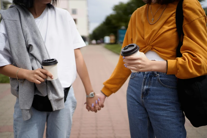 two women walking down a sidewalk while holding hands