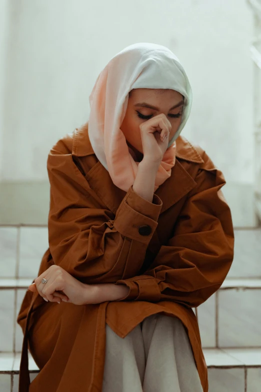 a woman sits and covers her face with a tissue