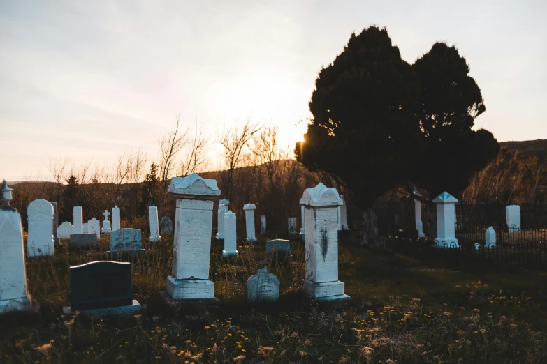 an old cemetery with headstones and trees at sunset