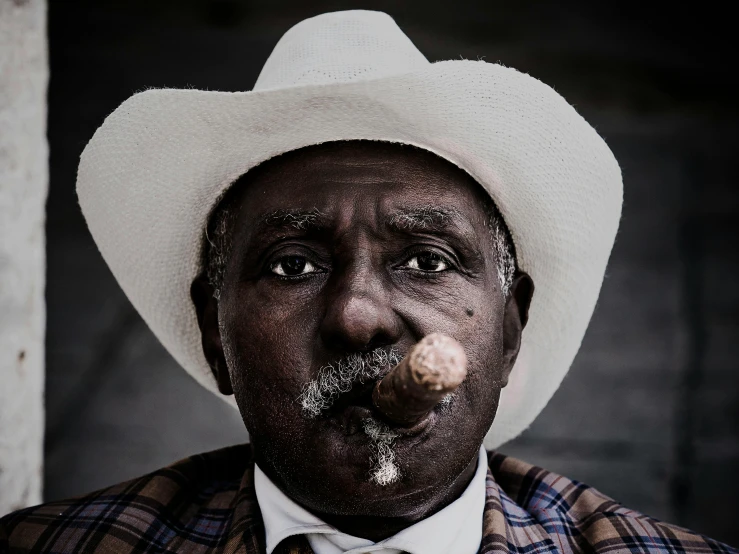 a man in a hat and plaid jacket smoking