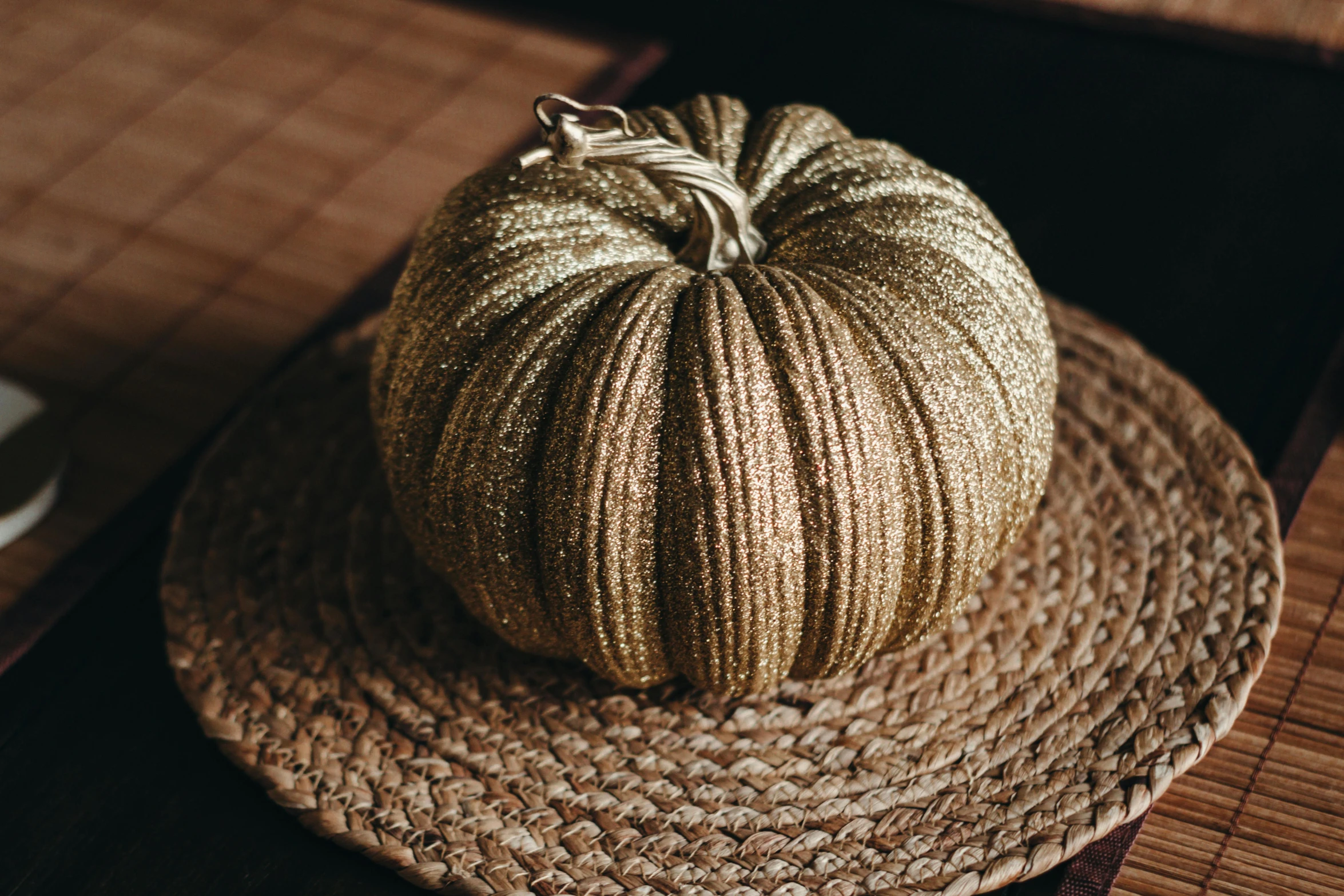 a round gold colored pumpkin on top of a straw mat