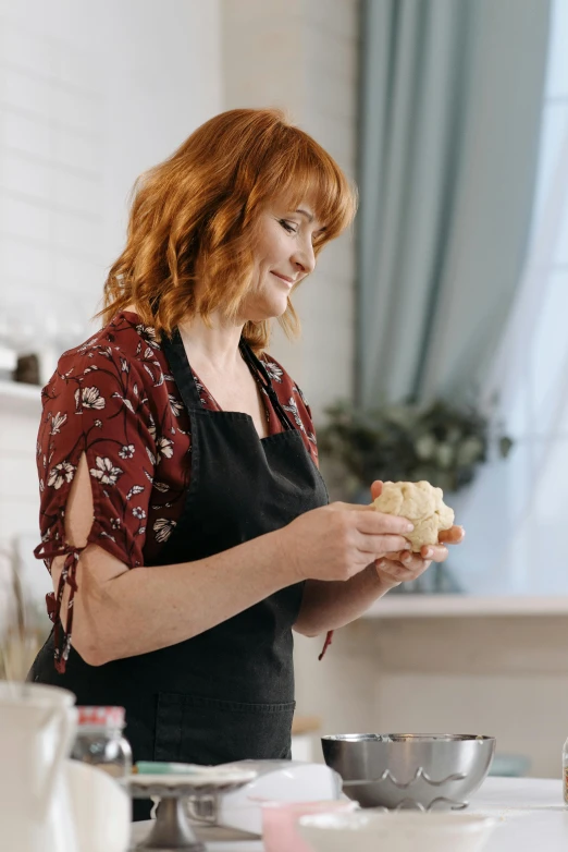 a woman with red hair standing by a stove preparing food