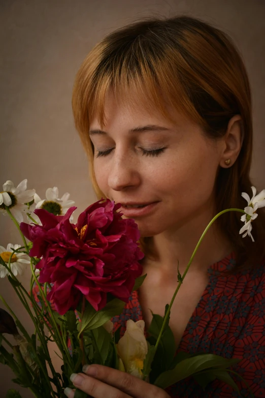 a woman is smelling a bouquet of flowers