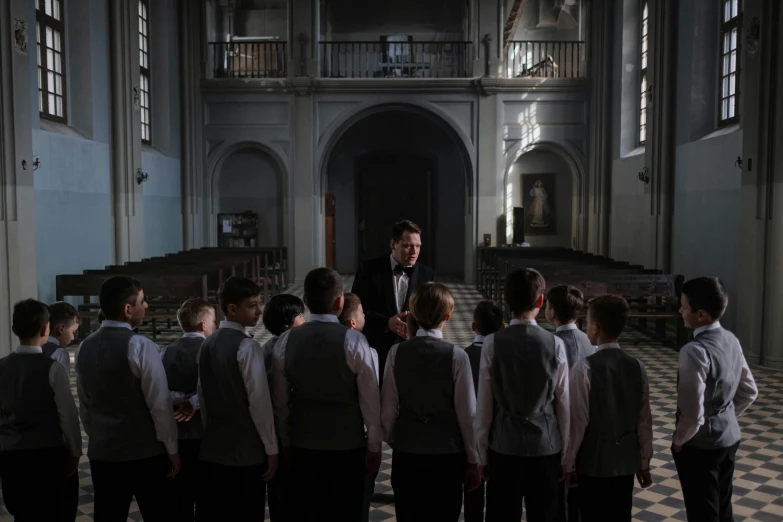 a man in a suit standing with a group of schoolboys