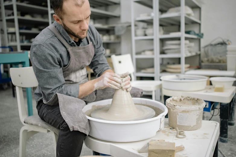 the potter is making a ceramic pot on the wheel