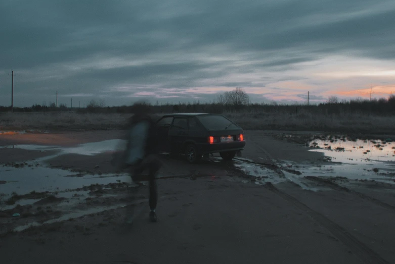 a car driving down a road near a swamp at night