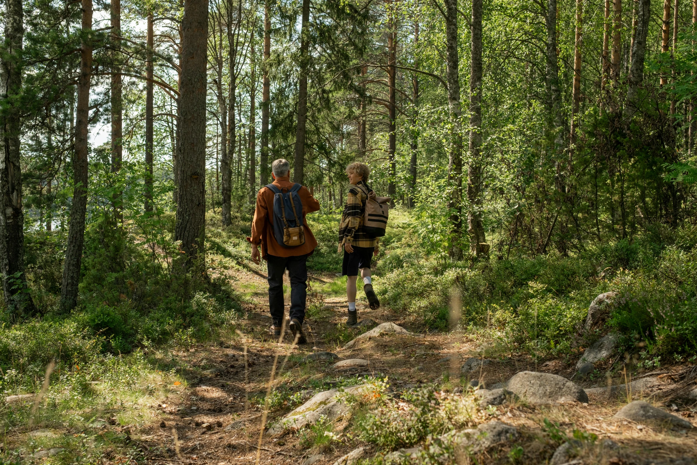 two people with backpacks are walking through the woods