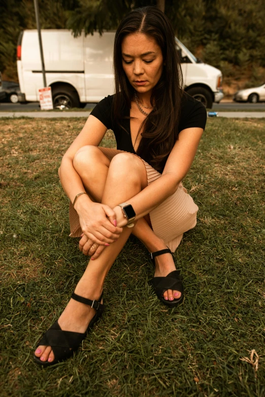 a woman is sitting on grass in a park