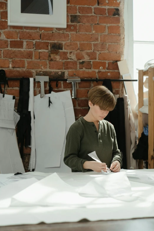 a woman sits at a table working on paper