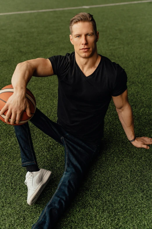 a man sitting on the grass holding a basketball