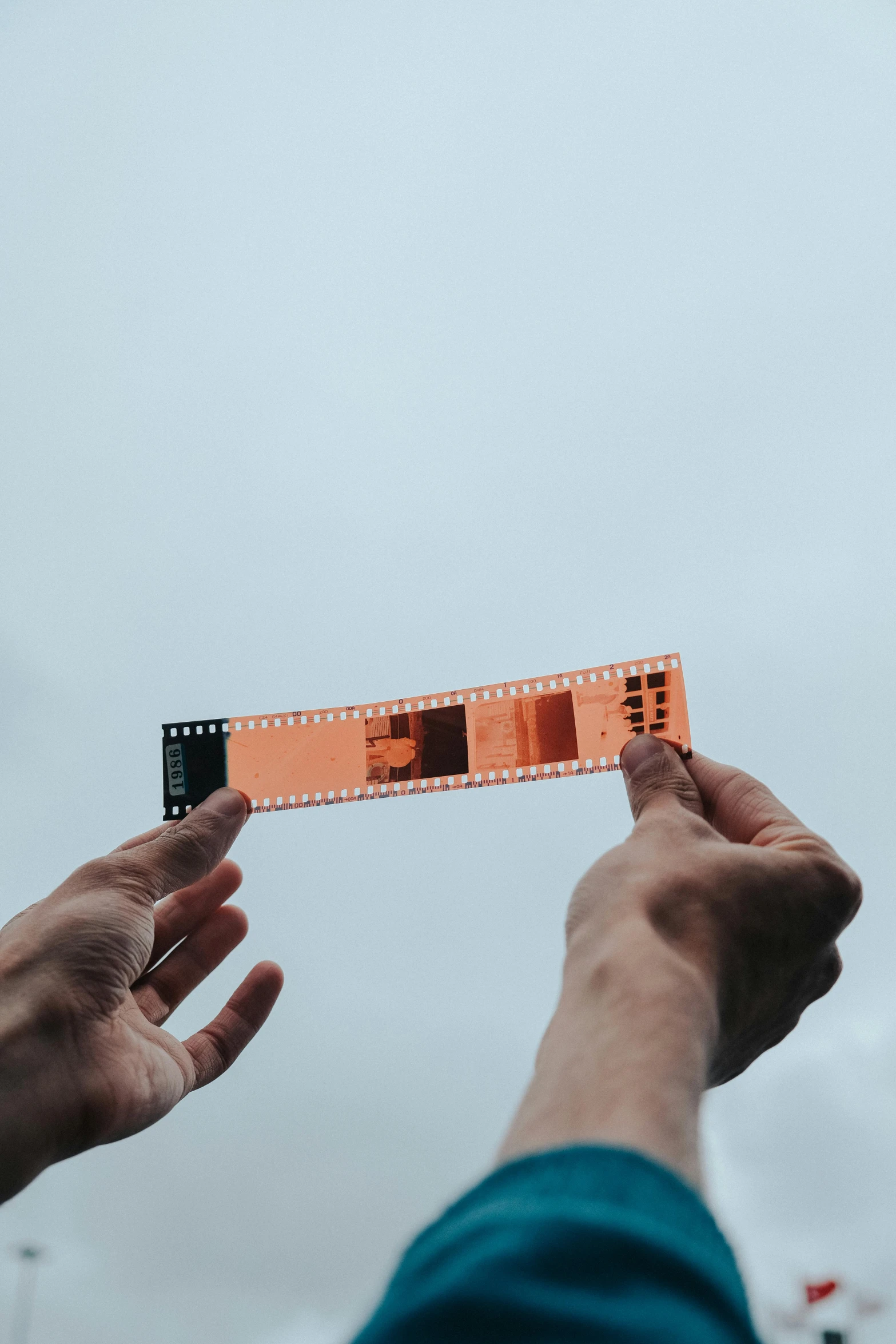 the person holds a small camera like object with orange squares