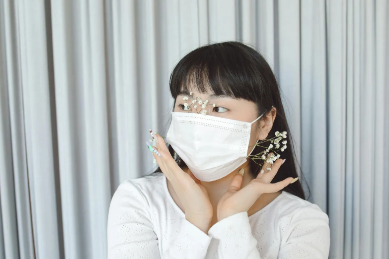 woman with mask on her face holding up a white object