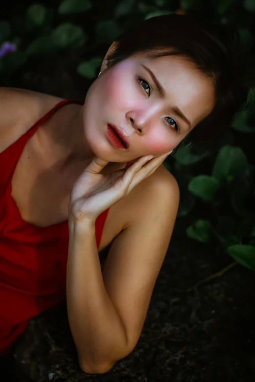 a young woman is sitting outside in a red dress