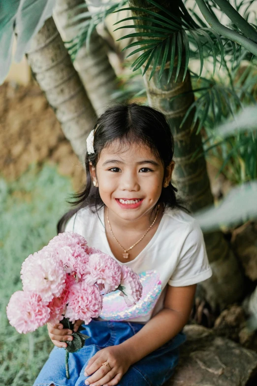 a girl sitting outside with a bunch of flowers