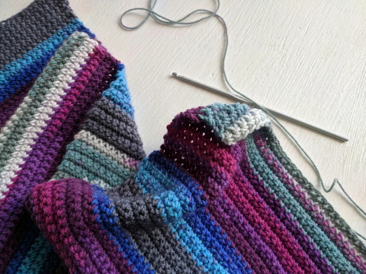 a close up view of two crocheted scarfs, one with a hole in the middle
