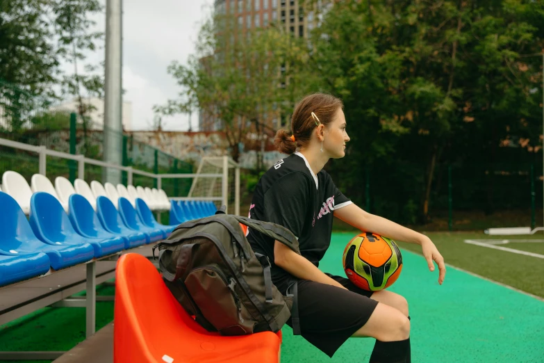 a girl sitting with her ball and a backpack