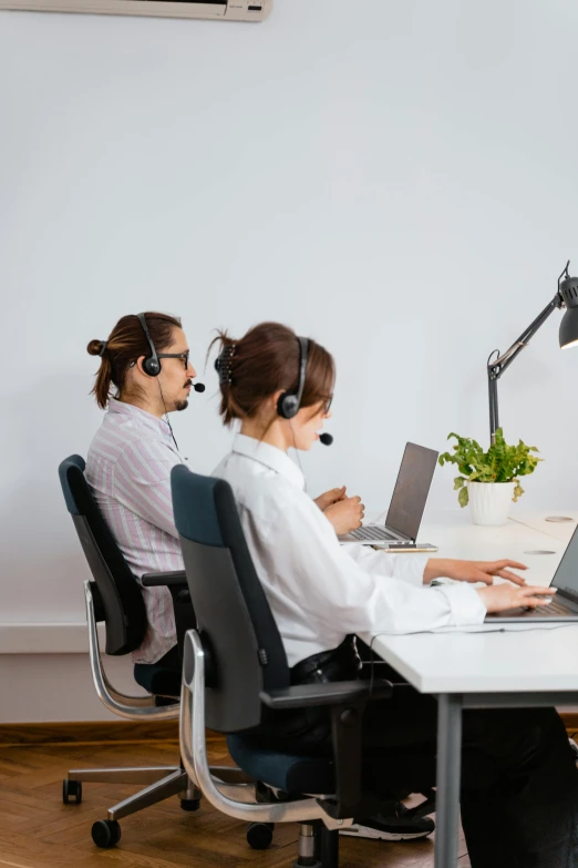 a couple of people siting in front of a computer screen