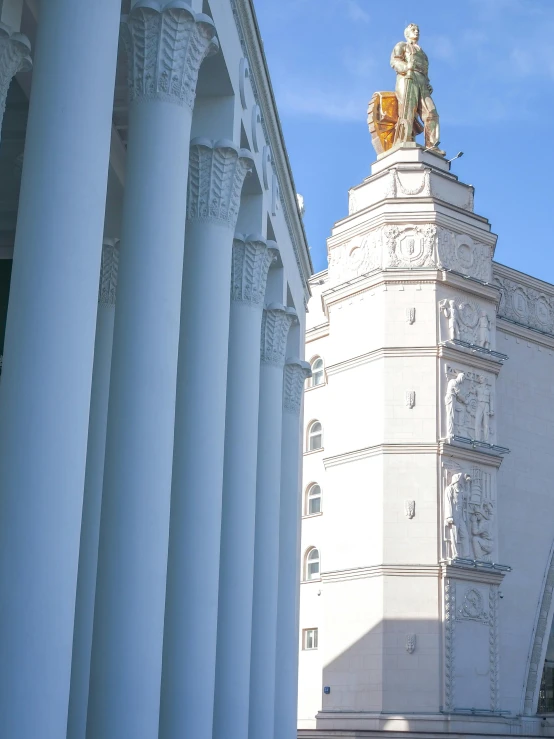 a large tall white building with arches and statues on the side