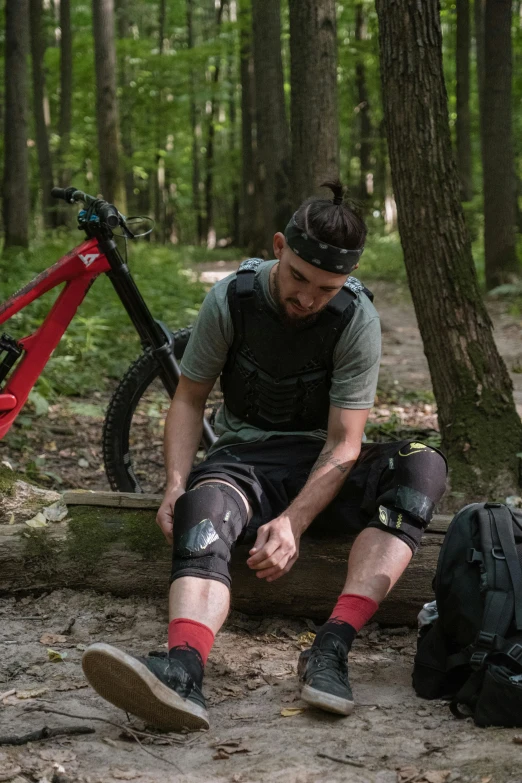 a man is sitting on a log in the woods