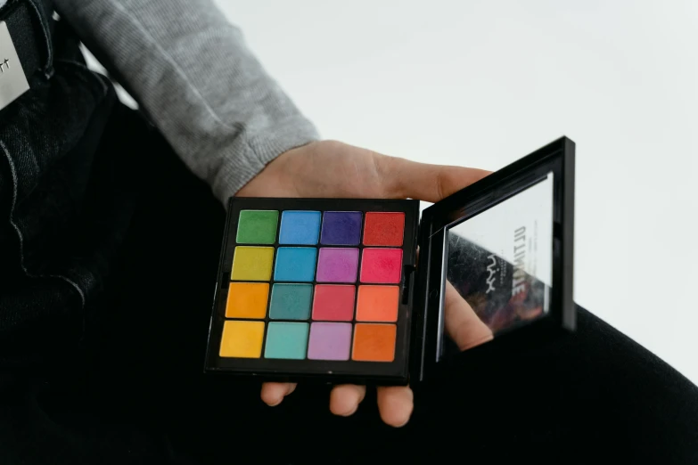 a man's hand holding a color cubed in front of his back