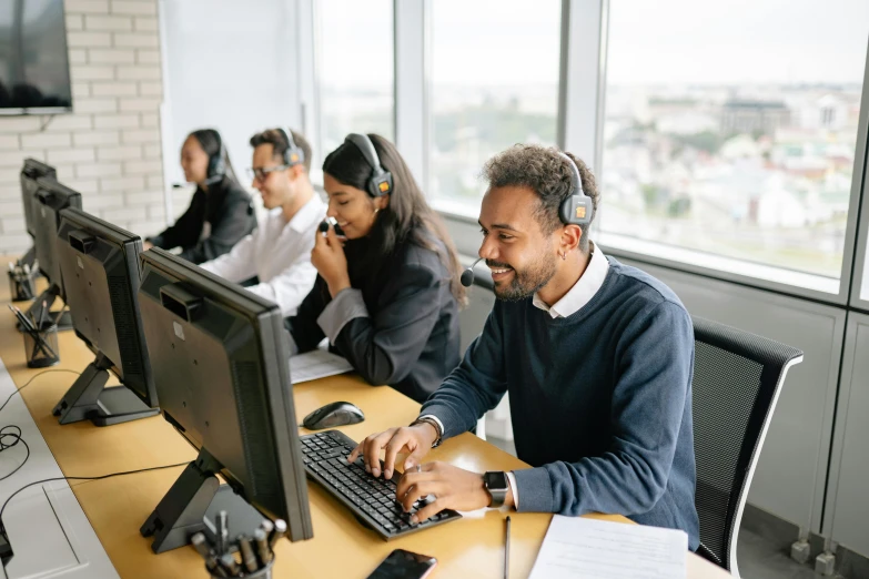 several young people working in an office on computer screens