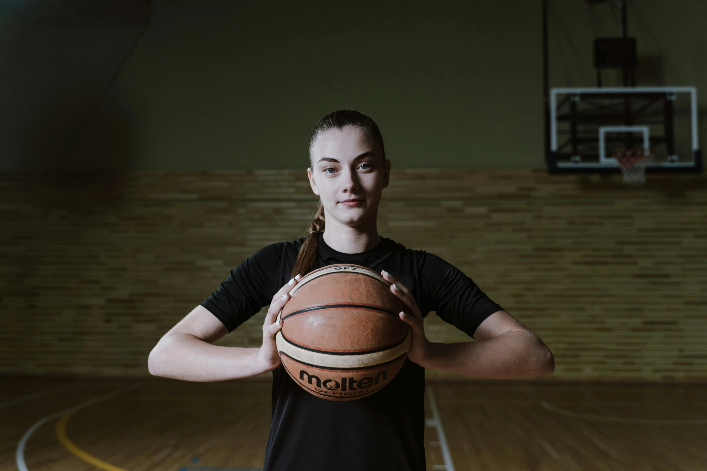 woman holding a basketball in her hands in an indoor gym