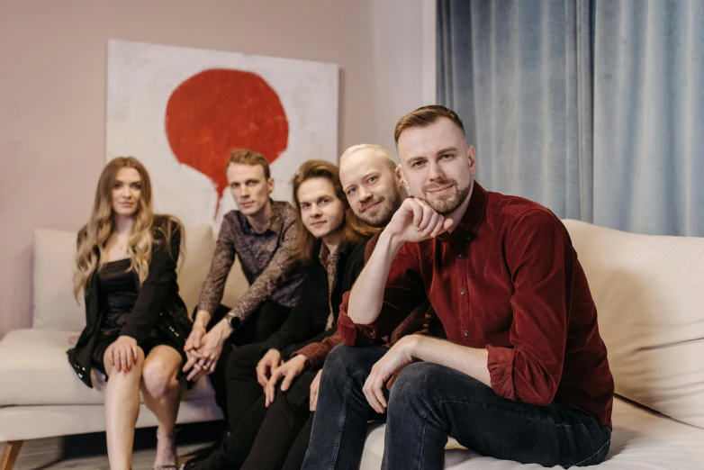 group of people seated on a couch together in front of a wall