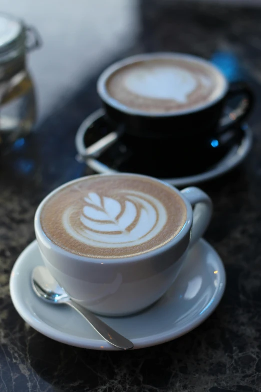 two cups of coffee are set on top of a saucer