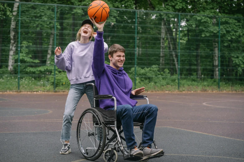 a young man on a wheelchair holding up a basketball