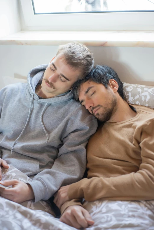 a man and woman sleeping in bed looking at a cell phone