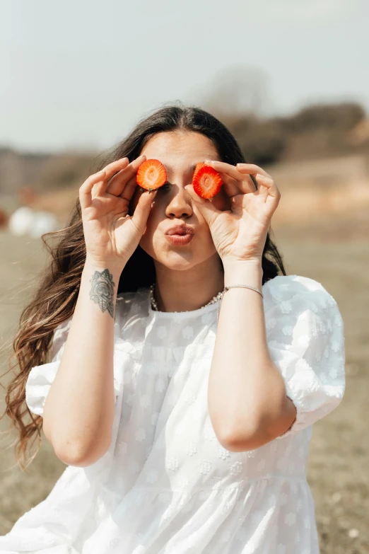 a woman is holding two carrots over her eyes