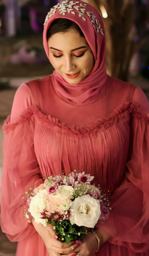 a woman in red wearing a hijab holding flowers
