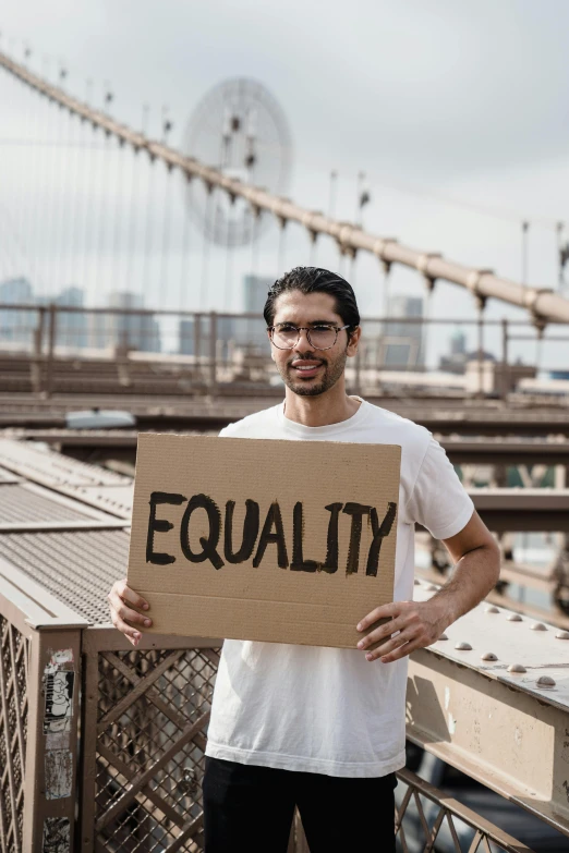 a man is standing on a bridge with a sign in his hands