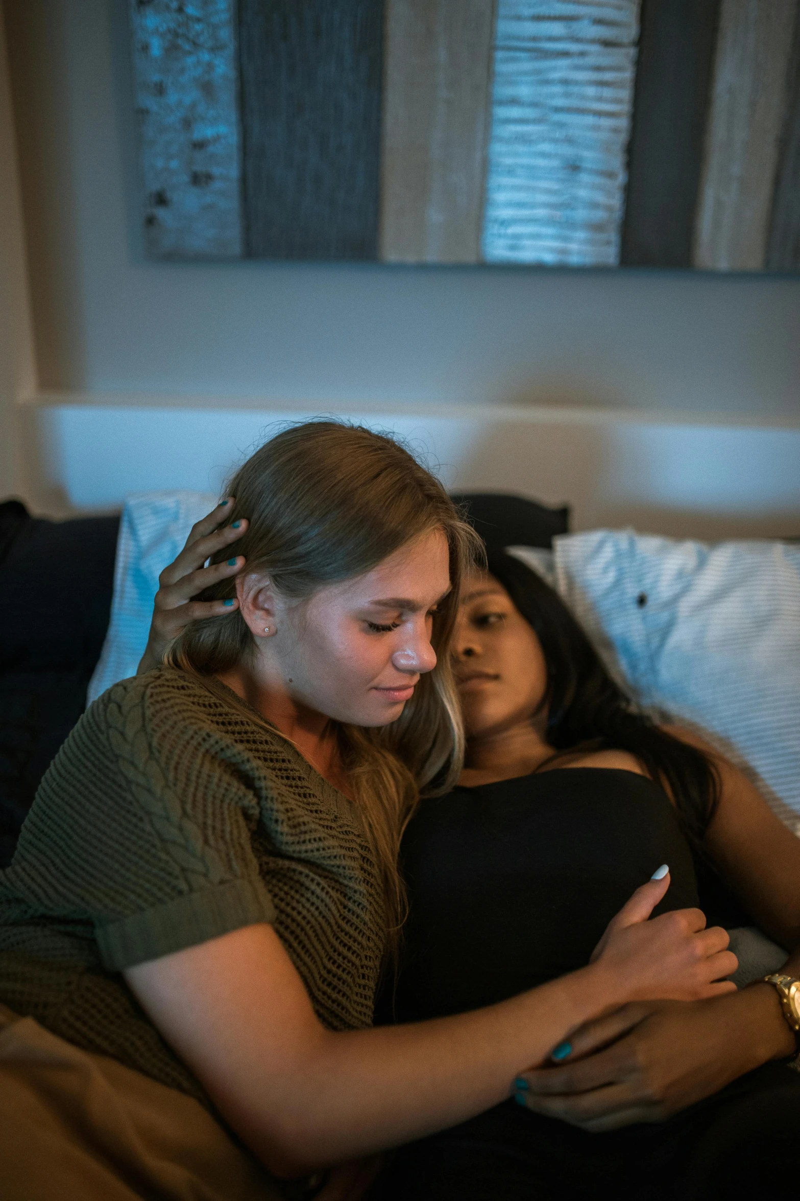 two woman laying in bed, one is emcing the other