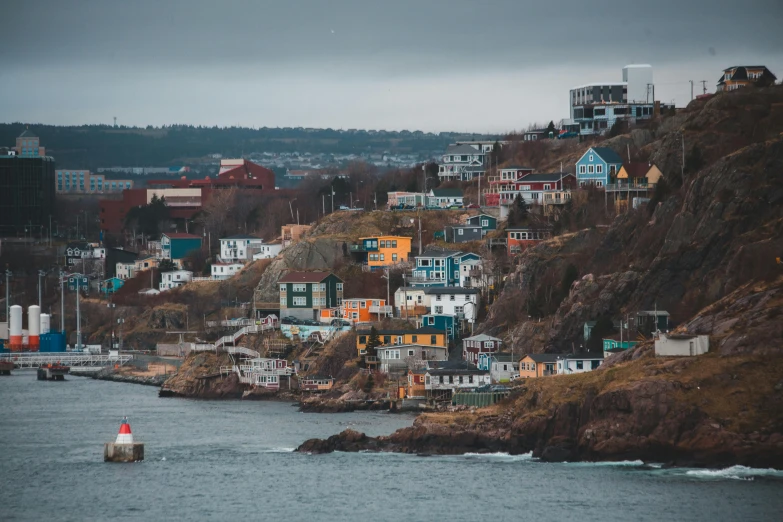 many houses on the side of a hillside near a body of water