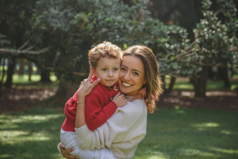 a woman is holding a little boy in the park