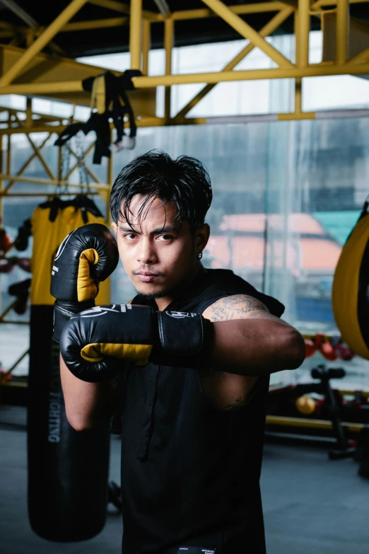 a young man wearing black is standing in a gym