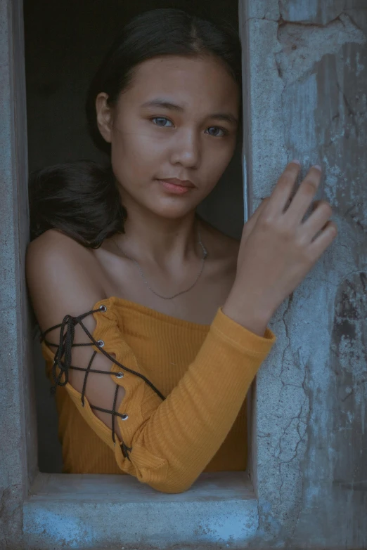 an asian woman with hand in window looking into camera