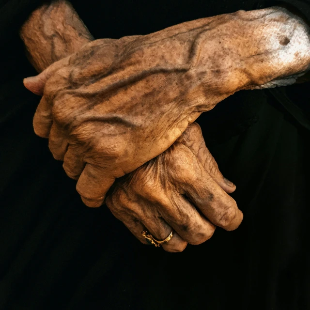 hands of a woman with their hands tied up and wearing gold rings