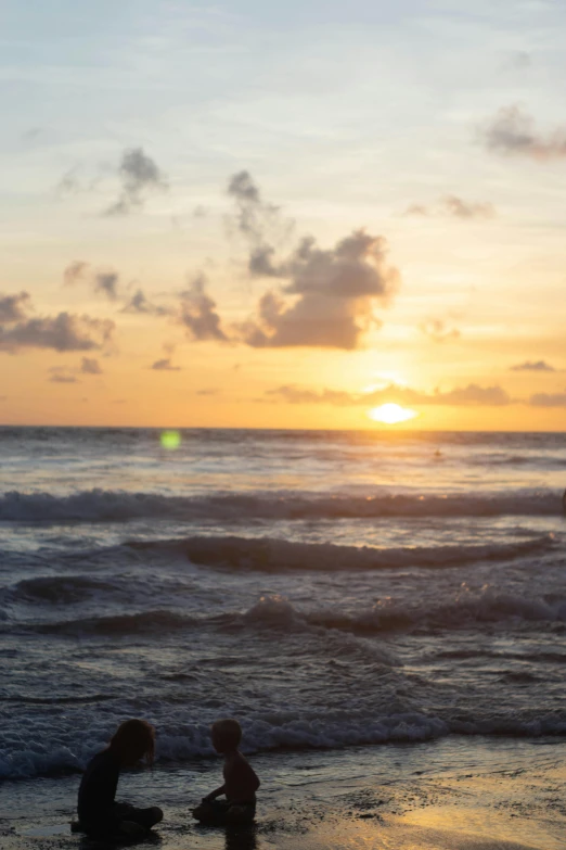 a person with child on the beach at sunset