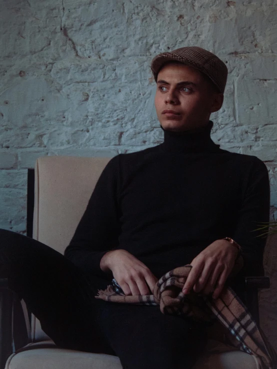 a man with a brown hat sits on a couch