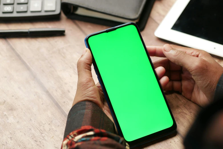 a man holding up a green screen on his cellphone
