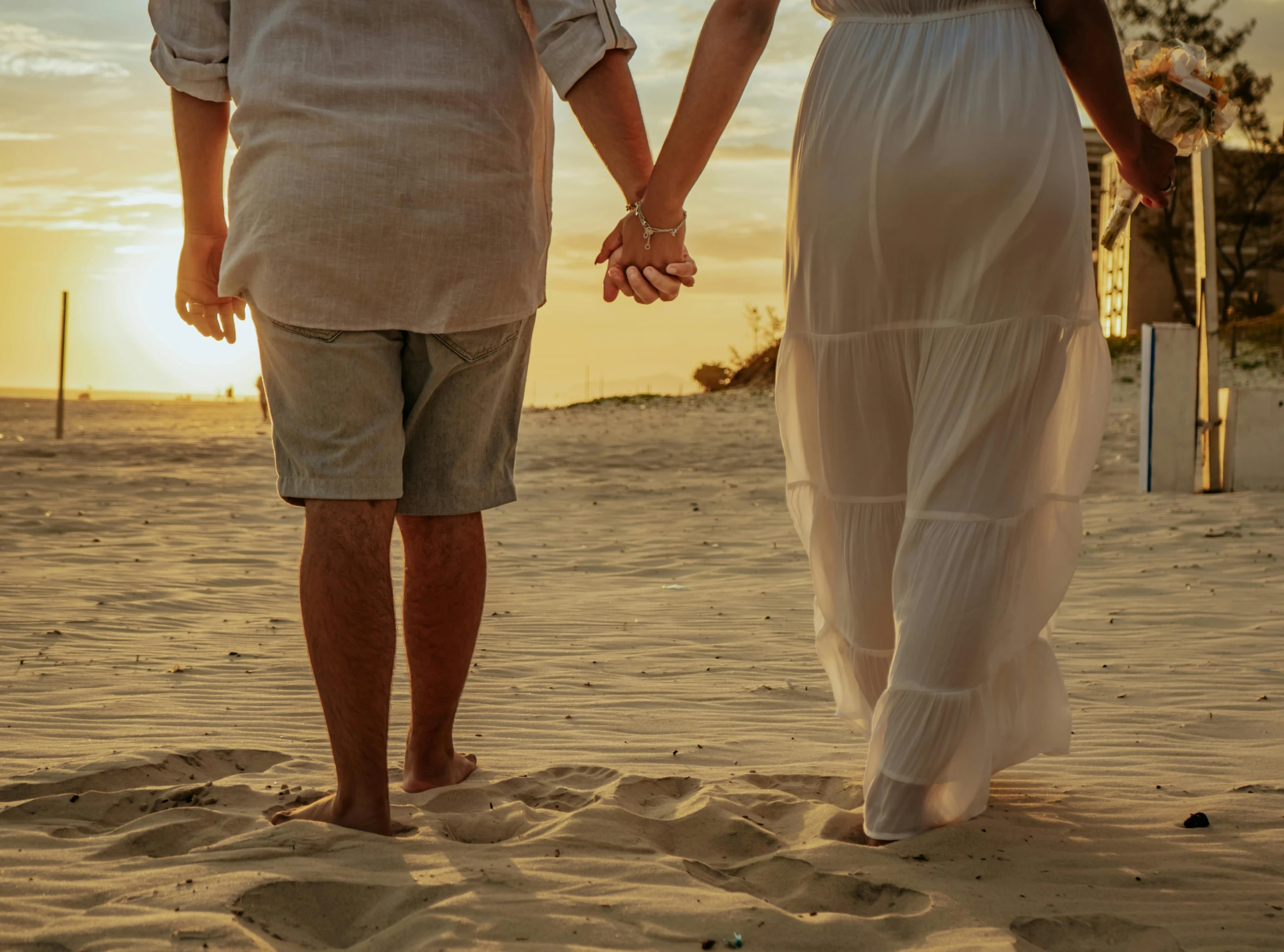 the man and woman are holding hands on the beach