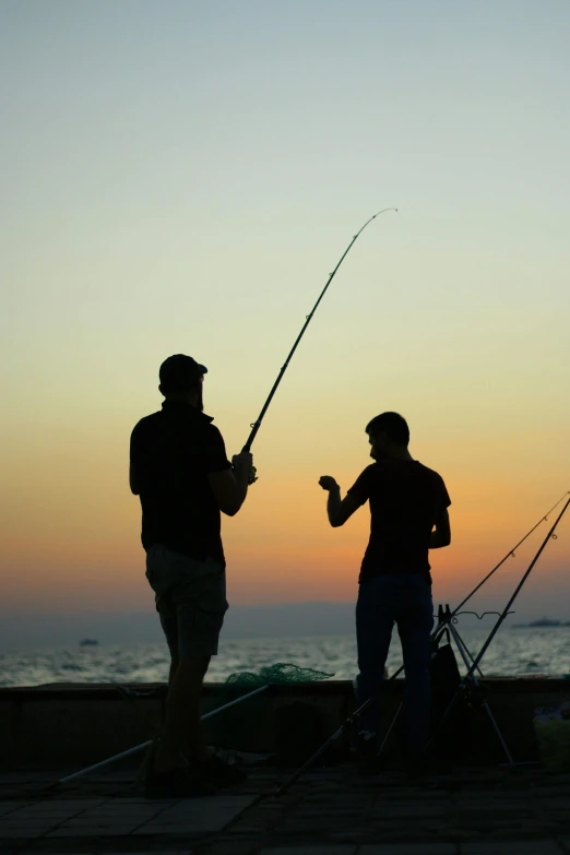 a couple of people that are standing near some fishing rods