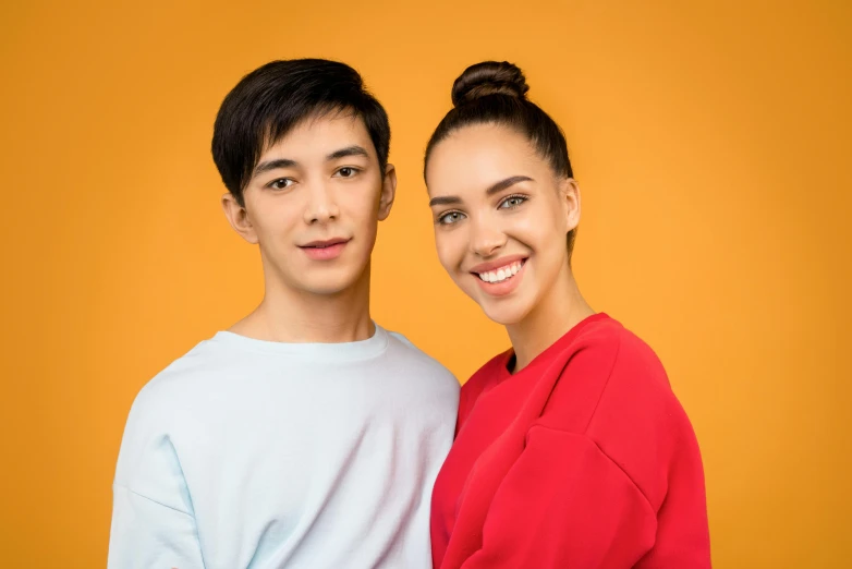 the couple is posing for a picture in front of an orange background