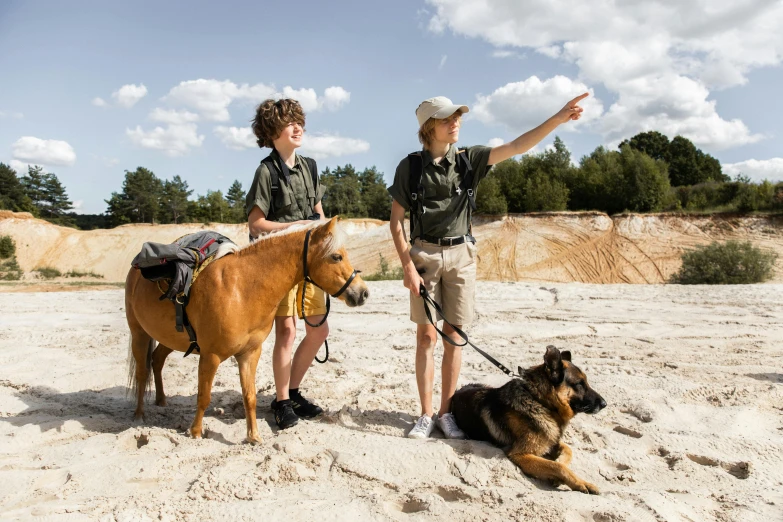 two people and their dog on a sandy beach