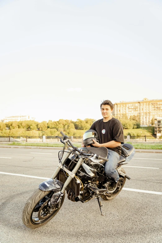 man sitting on motorcycle posing for po with cityscape in background